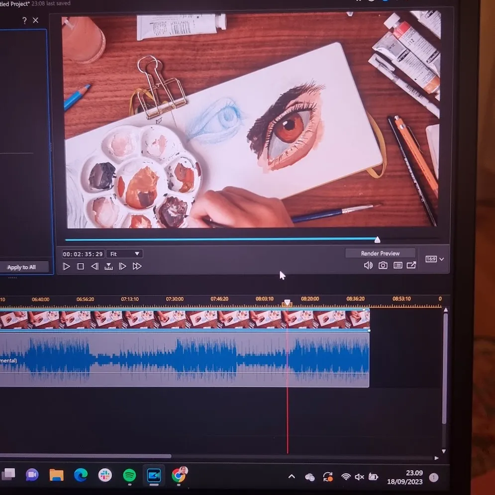 Video footage open in an editor - it is a high quality shot of a sketchbook open on a desk with some pencils, paint tubes, and brushes scattered around